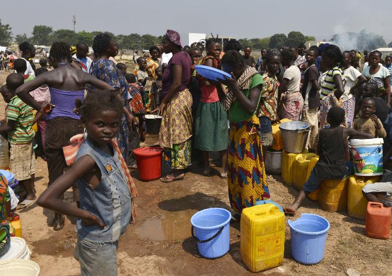 A girl drinks as internally-displaced people wait for water at the IDP camp near the international airport in Bangui on December 23, 2013