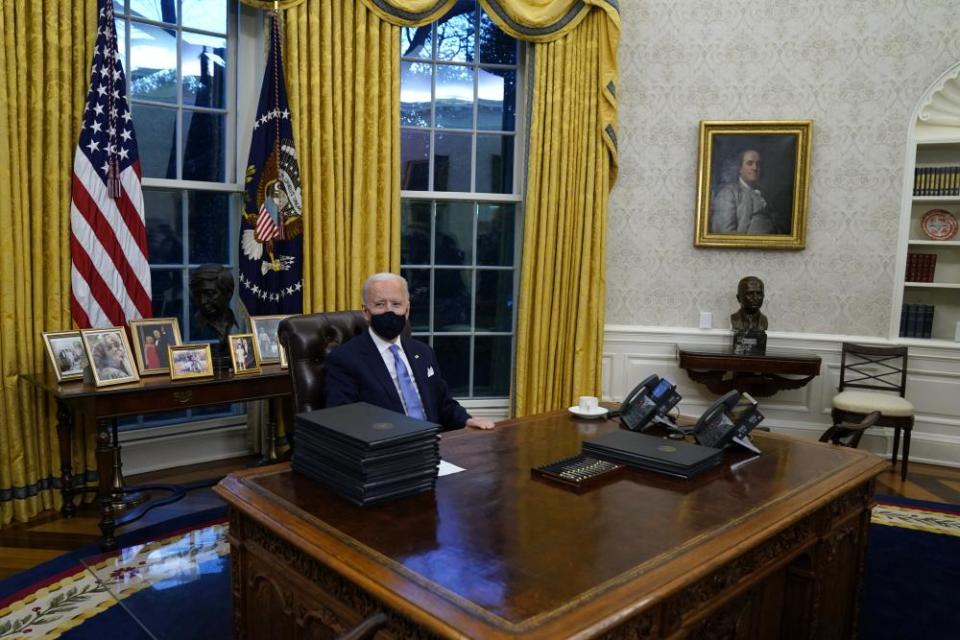 Biden signs his first executive orders in the Oval Office.