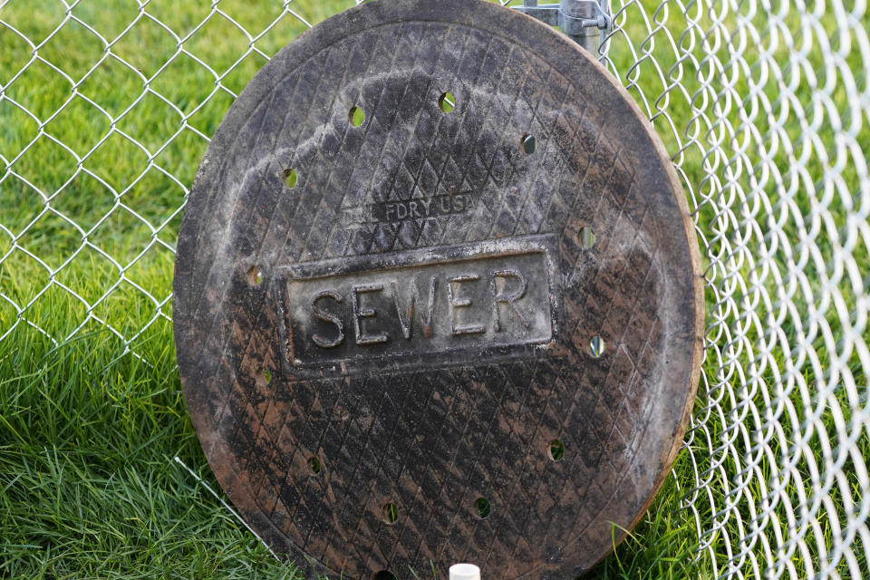 A sewer manhole cover is shown near Davis Hall at Utah State University Wednesday, Sept. 2, 2020, in Logan, Utah. About 300 students quarantined to their rooms this week, but not because anyone got sick or tested positive. Instead, the warning bells came from the sewage. Colleges around the country are monitoring wastewater in hopes of stopping coronavirus outbreaks before they get out of hand. Utah State became at least the second school to quarantine hundreds of students after sewage tests detected the virus. (AP Photo/Rick Bowmer)
