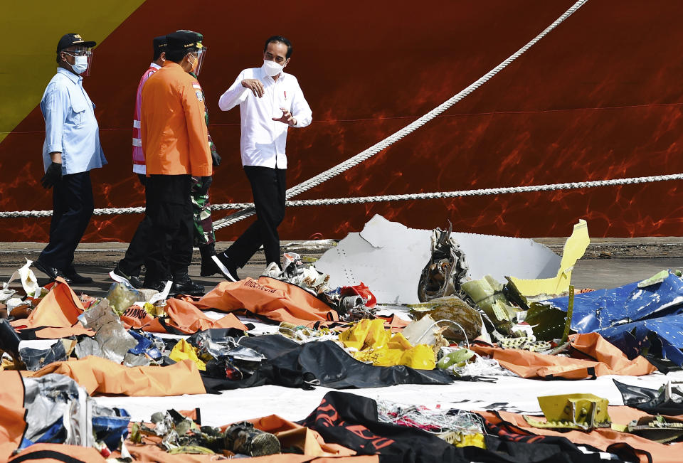 In this photo released by the Indonesian Presidential Palace, President Joko Widodo, right, talks to the Chairman of the National Transportation Safety Committee Soerjanto Tjahjono, left, Chief of National Search and Rescue Agency Bagus Puruhito, center, Transportation Minister Budi Karya Sumadi, and Navy Chief of Staff Adm. Yudo Margono, partially seen, rear center, as they inspect pieces of the Sriwijaya Air flight SJ-182 retrieved from the Java Sea where the passenger jet crashed on Jan. 9, at Tanjung Priok Port in Jakarta, Indonesia, Wednesday, Jan. 20, 2021. The Indonesian leader on Wednesday reassured relatives of the passengers killed when the plane nosedived into the Java Sea that compensation is paid to family members struggled with grief. (Laily Rachev, Indonesian President Palace via AP)