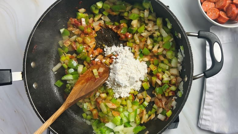 adding flour to vegetables in pan