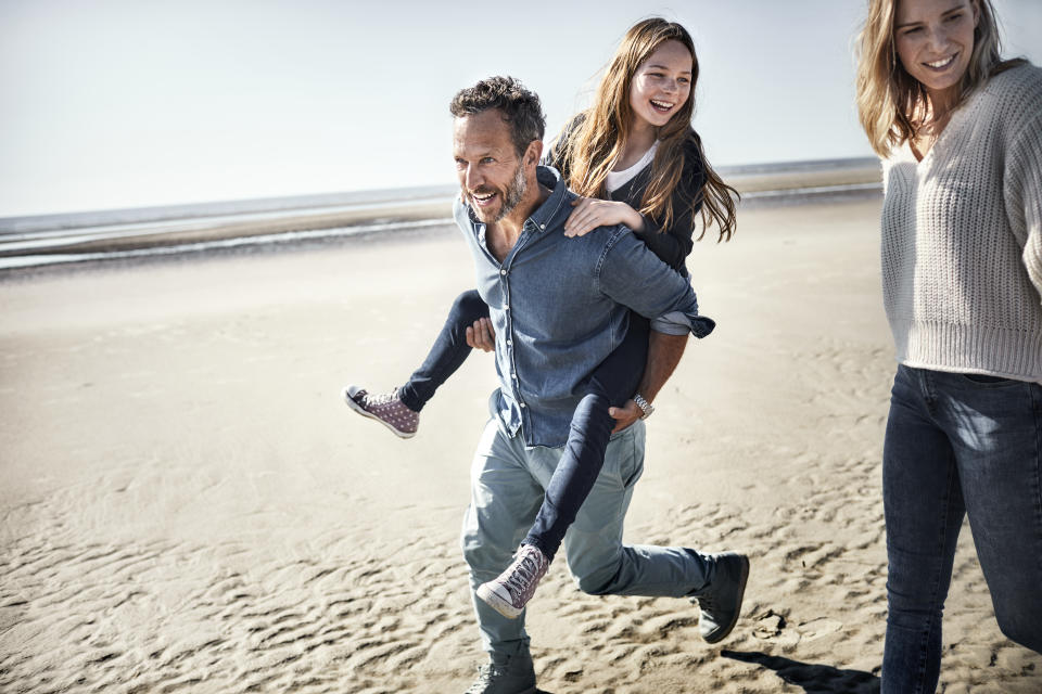 Father carrying daughter piggyback on the beach