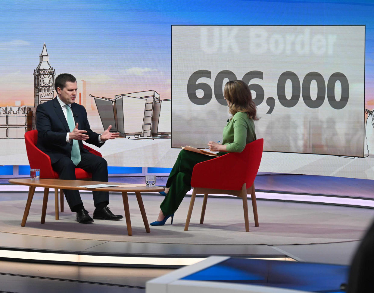 Robert Jenrick and Laura Kuenssberg in front of a screen showing the UK's record net migration figures. (PA)