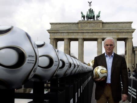 Franz Beckenbauer, President of Germany's World Cup organising committee, holds a golden soccer ball during a presentation next to the Brandenburg gate in Berlin April 18, 2006. REUTERS/Tobias Schwarz/File Photo