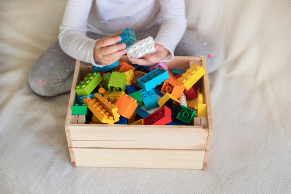 child sorting lego bricks in crate