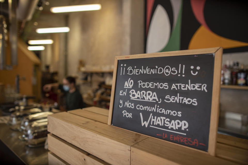 A banner reading in Spanish: "Welcome, we cannot serve in the bar. Sit down and we communicate by WhatsApp" is pictured at La Francachela restaurant in Madrid, Spain, Friday, March 26, 2021. Experimenting with cutting back one workday per week is about to go nationwide in Spain. A 3-year pilot project will be using 50 million euros ($59 million) from the European Union's massive coronavirus recovery fund to compensate companies as they resize their workforce or reorganize production workflows to adapt to a 32-hour working week. (AP Photo/Manu Fernandez)