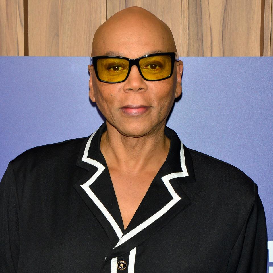 Celebrity in a black shirt with white trim, posing at a Paramount event