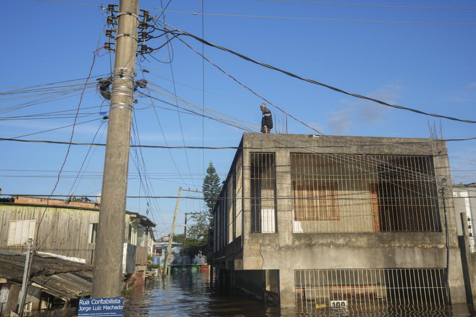A resident stands on the rooftop of his home partially submerged by flood waters from heavy rains, in Porto Alegre, Rio Grande do Sul state, Brazil, Thursday, May 9, 2024. (AP Photo/Andre Penner)