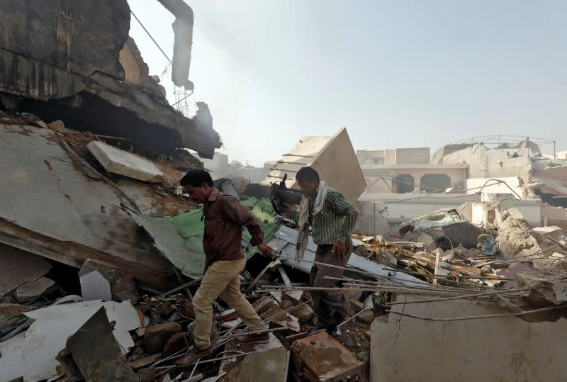 FILE PHOTO: Men walk on the debris at the site of a passenger plane crash in a residential area near an airport in Karachi