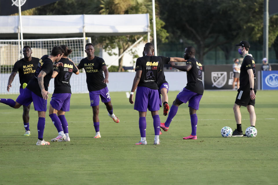 Orlando City players warm up wearing Black Lives matter t-shirts before an MLS soccer match against the Montreal Impact, Saturday, July 25, 2020, in Kissimmee, Fla. (AP Photo/John Raoux)