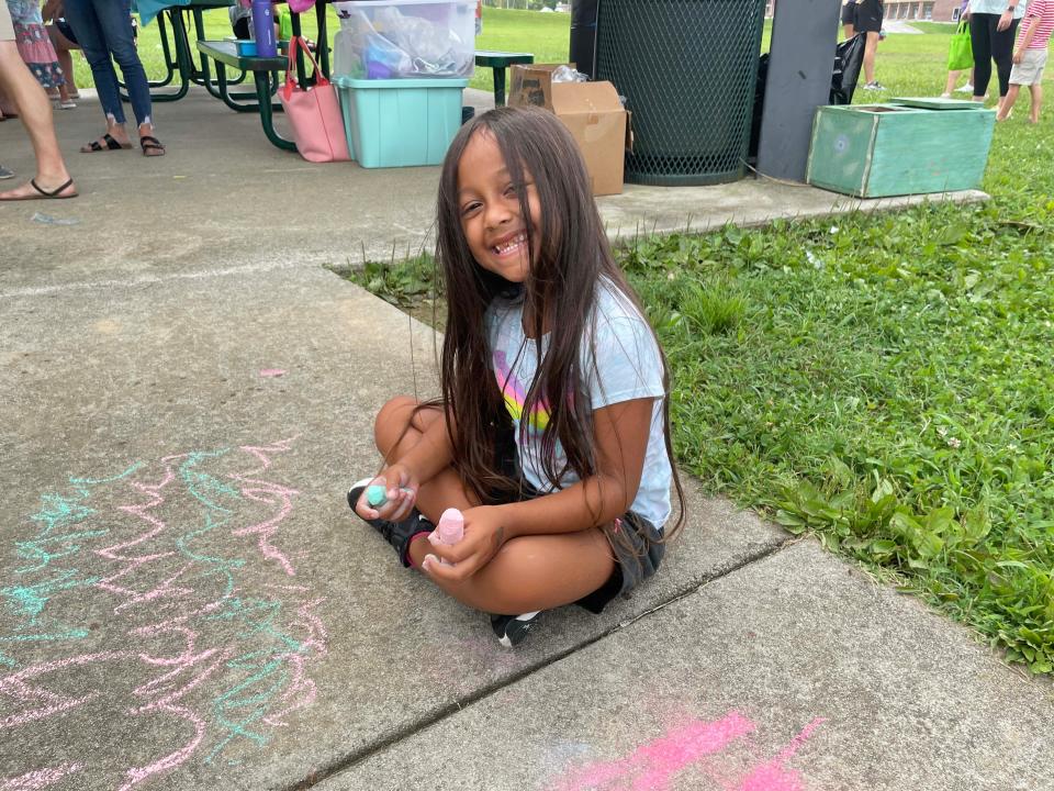 Natalynn Wijawa flashes a smile while working on her sidewalk chalk masterpiece at the annual Hardin Valley Elementary School Popsicle Party held at the school Sunday, Aug. 14, 2022.