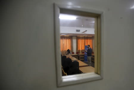 Bilal Yassin (R), project's coordinator and a trainer in Islamic matters, is pictured through a door glass as he gives marriage counseling class to Palestinian brides, at the Islamic University in Gaza City January 19, 2016. REUTERS/Suhaib Salem