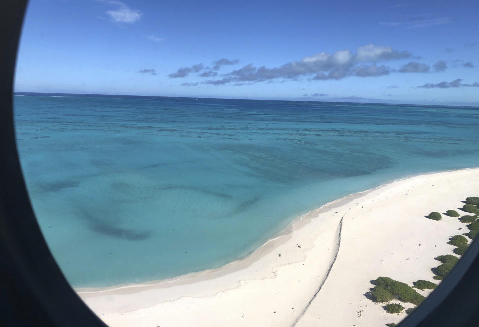 In this Tuesday, Oct. 15, 2019 photo, the shoreline of Midway Atoll in the Northwestern Hawaiian Islands is shown from a landing airplane. Deep-sea explorers scouring the world's oceans for sunken World War II ships are honing in on a debris field deep in the Pacific. Weeks of grid searches around the Northwestern Hawaiian Islands already have led the research vessel Petrel to one sunken battleship, the Japanese aircraft carrier Kaga. (AP Photo/Caleb Jones)