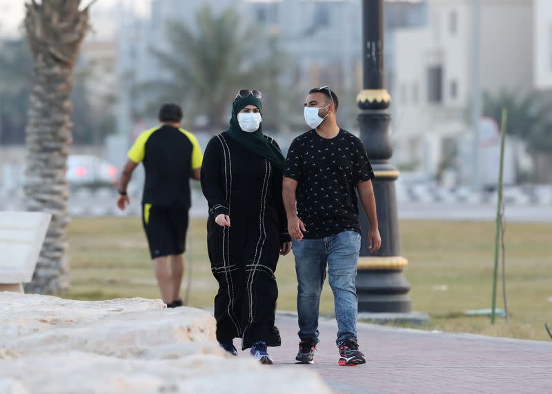 A couple wear a protective face mask, as they walk, after Saudi Arabia imposed a temporary lockdown on the province of Qatif, following the spread of coronavirus, in Qatif