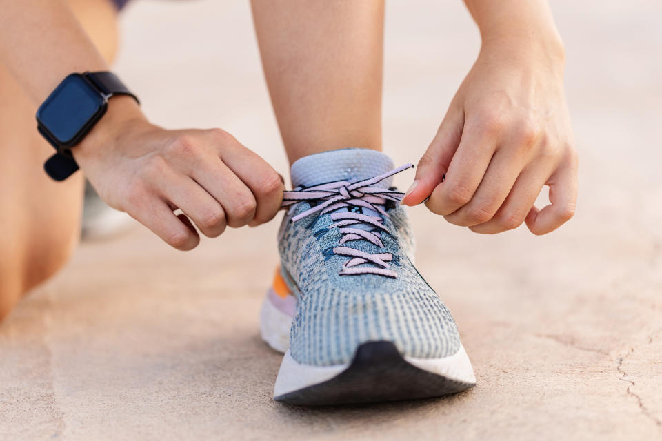 Close-up view of female jogger tying laces of her sport shoes before running exercise routine. Motivation, healthy lifestyle and fitness concept.