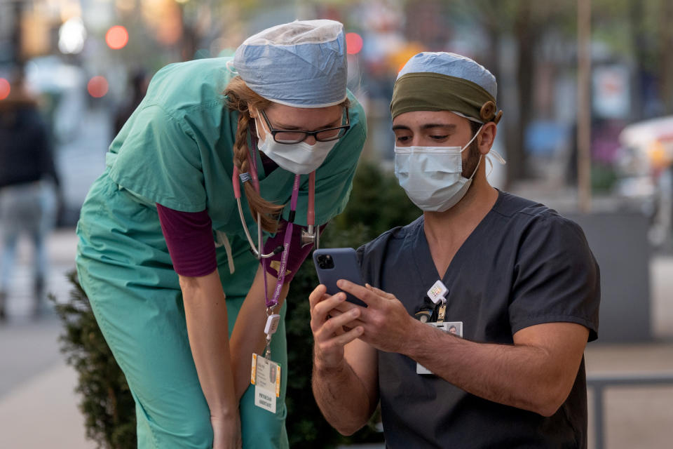 NEW YORK, NEW YORK - APRIL 22: Two healthcare workers wearing masks look at a photo in front of the Lenox Health Greenwich Village Hospital amid the coronavirus pandemic on April 22, 2020 in New York City, United States. COVID-19 has spread to most countries around the world, claiming over 182,000 lives with over 2.6 million cases. (Photo by Alexi Rosenfeld/Getty Images)