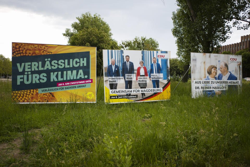 Election campaign posters from the Greens and Merkel's Christian Democratic Union party stand near a road in the federal state Saxony-Anhalt's capital Magdeburg, Germany, Wednesday, June 2, 2021. The state vote on Sunday, June 6, 2021 is German politicians' last major test at the ballot box before the national election in September that will determine who succeeds Chancellor Angela Merkel. The from left: A poster of the Green Party with the slogan: reliable for climate reliable for Saxony-Anhalt, center a poster of the CDU showing candidates and reading; "together for Magdeburg' and right a poster showing ruling CDU governor Reiner Haseloff with bis wife Gabriele Haseloff and the slogan: Out of love for our homeland'. (AP Photo/Markus Schreiber)