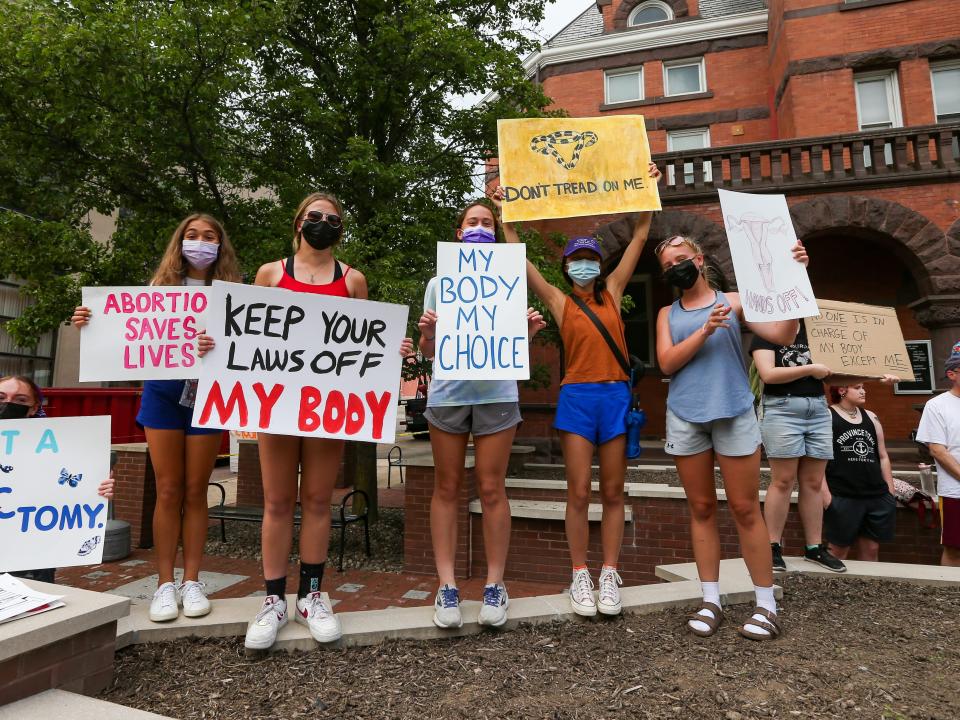 Abortion rights protesters hold signs.