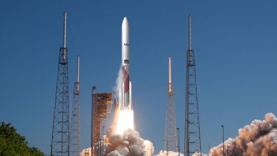 a white and red rocket launches into a blue sky.