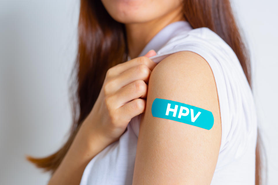 HPV (Human Papillomavirus) Teenager woman showing off an blue bandage after receiving the HPV vaccine. viruses Some strains infect genitals and can cause cervical cancer. Woman health concept.