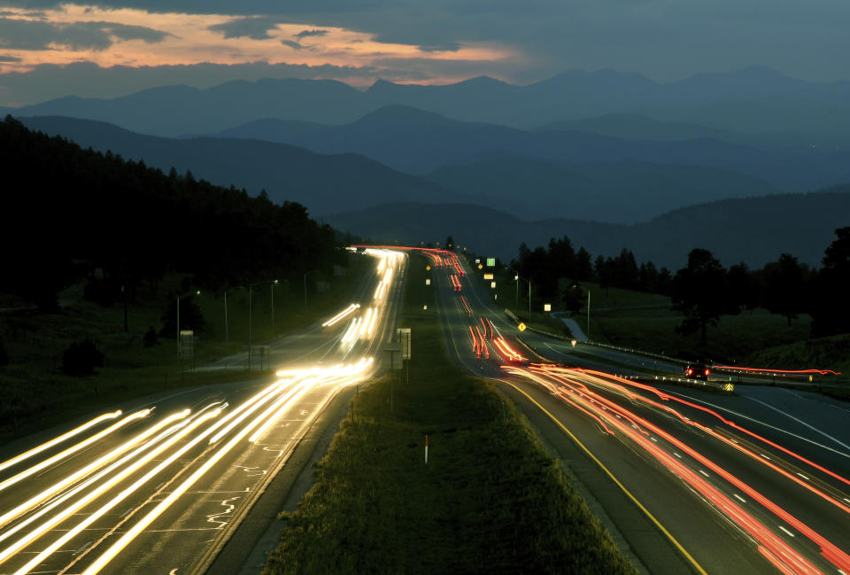 In this Sept. 8, 2017 time exposure photo, the sun sets as traffic moves along Interstate 70 west of Denver. Heavy ski traffic along the interstate has been common for years, but Colorado's recent population boom is making it increasingly challenging for transportation officials who deal with a bare-bones budget. (AP Photo/Thomas Peipert)