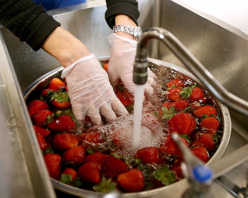 Jeannie Fein washes strawberries while preparing the fresh fruit for the lunch period during a tour of East Middle School's cafeteria in Braintree on Thursday