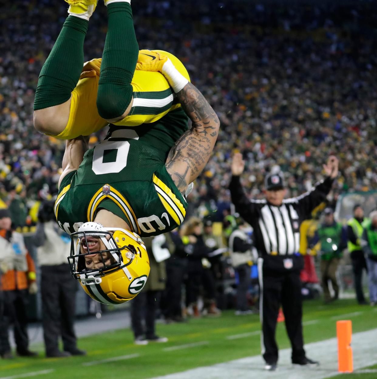 Green Bay Packers wide receiver Christian Watson does a back flip in the end zone after scoring on a long reception.