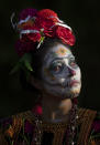 Gabriela Ruiz is dressed as a "Catrina" to perform in a play promoting the upcoming Day of the Dead holiday, at the Nativita pier in the Xochimilco borough of Mexico City, Friday, Oct. 23, 2020. The iconic figures of skeletons with elegant wide-brimmed hats better known as Catrinas were created as satirical prints by Mexican artist Jose Guadalupe Posada sometime between 1910 and his death in 1913. (AP Photo/Marco Ugarte)