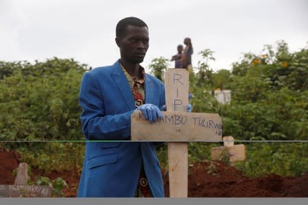 FILE PHOTO: A Congolese man holds a cross during the burial service of Congolese woman Kahambu Tulirwaho who died of Ebola, at a cemetery in Butembo