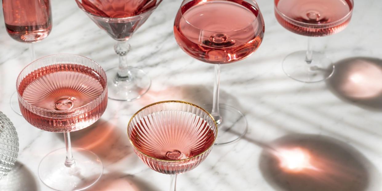 pink rose cocktail or mocktail with sunny summer light on white marble table and palm tree shadows