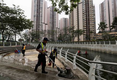 Worker clean the ground of a park in front of Bakrie Tower in Jakarta October 14, 2014. REUTERS/Beawiharta