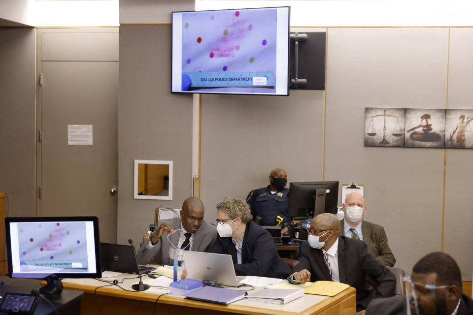 Defense attorney Kobby Warren, left, talks with private investigator Tonia Silva as an image of a lipstick stained pillow is shown to the court during the murder trial of Billy Chemirmir, right, at the Frank Crowley Courts Building in Dallas, Tuesday, Nov. 16, 2021. Chemirmir faces life in prison without parole if convicted of capital murder in the death of 81-year-old Lu Thi Harris. (Tom Fox/The Dallas Morning News via AP, Pool)