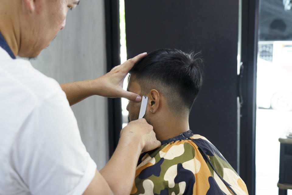 A barber working on a customer's sideburns