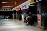 Women wearing face masks wait for customers at an electrical appliances store in Xianning