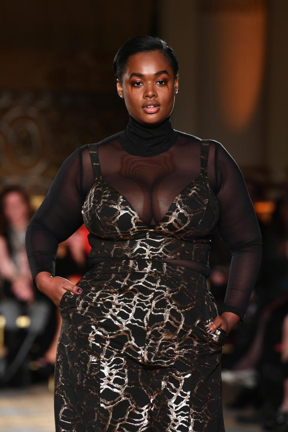 This model’s gorgeous curves are shown off in this metallic and sheer dress at Christian Siriano.