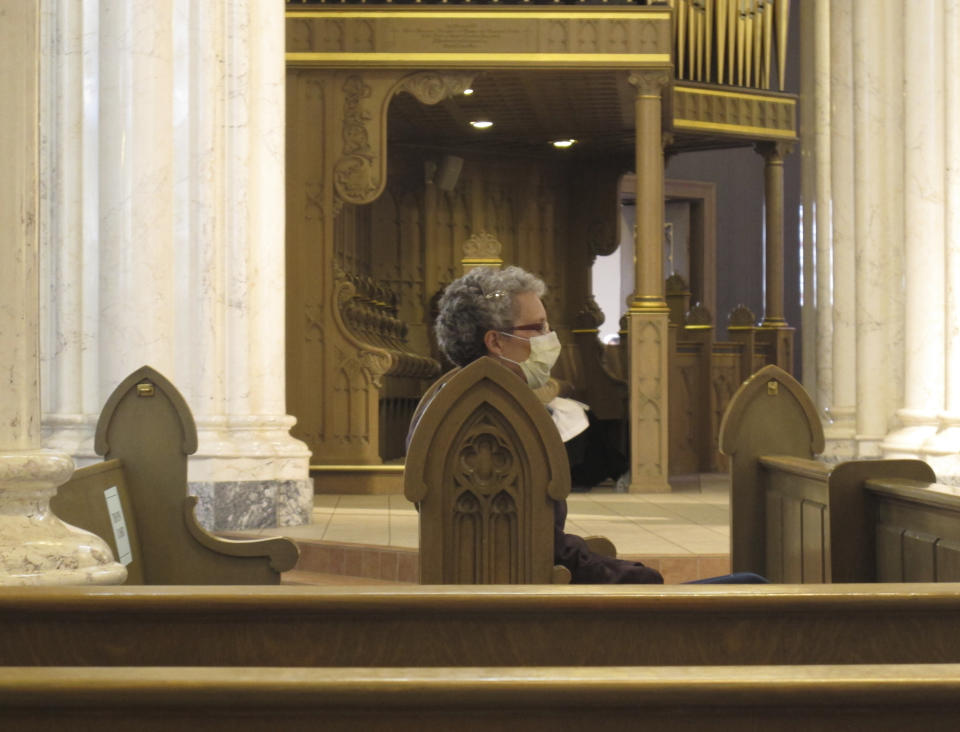 A congregant wears a face mask before mass at the Cathedral of St. Helena in Helena, Mont., Sunday, April 26, 2020. Church services resumed in Montana as the state began to ease restrictions meant to stop the spread of the coronavirus. (AP Photo/Matt Volz)