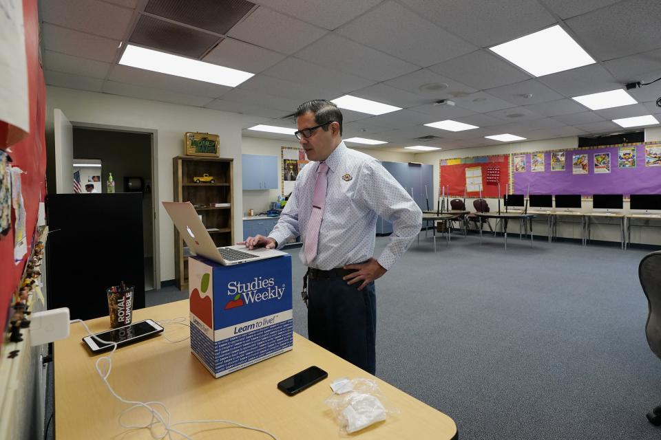 Teacher Eugene Montoya works with students in a remote learning class at the Valencia Newcomer School, Tuesday, Sept. 2, 2020, in Phoenix. Communicating during the coronavirus pandemic has been trying for parents and students at the Phoenix school for refugees who speak a variety of languages and are learning to use technology like iPads and messaging apps. (AP Photo/Ross D. Franklin)