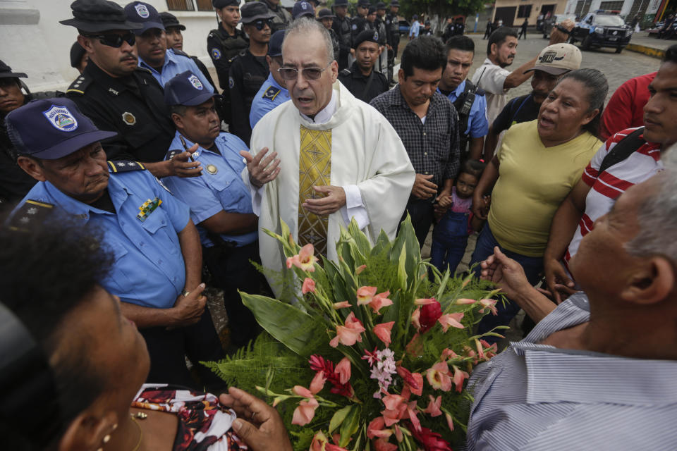 Father Edwin Roman attempts to convince the police to allow relatives of imprisoned and dead anti-government demonstrators to enter the San Miguel Arcangel Church in Masaya, Nicaragua, Thursday, Nov. 14, 2019. The relatives have started a hunger strike to demand the freedom of their relatives, jailed for protesting against the government of President Daniel Ortega. (AP Photo/Alfredo Zuniga)