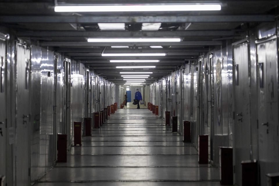 A worker walks along the corridors leading to wards at the Leishenshan Hospital which was constructed in a parking lot from prefabricated modules in two weeks in Wuhan in central China's Hubei province, Saturday, April 11, 2020, as the city dealt with a rush of patients in the early days of the coronavirus outbreak. The hospital closed on April 9 but still has 14 patients, mainly elderly with underlying complications. (AP Photo/Ng Han Guan)