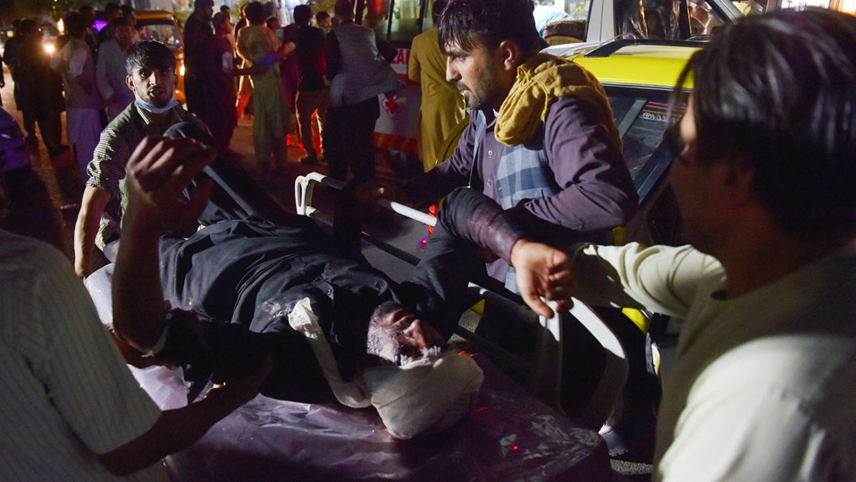 Medical and hospital staff bring an injured man on a stretcher for treatment after two blasts outside the airport in Kabul, Afghanistan, Thursday. (Photo by Wakil Koshar/AFP via Getty Images)