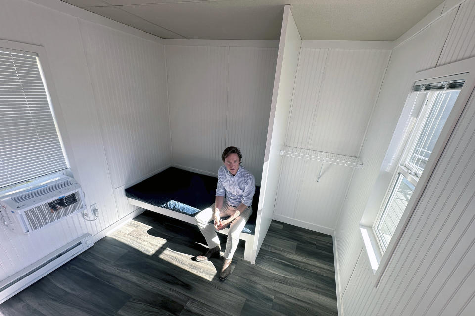 Denver Mayor Mike Johnston sits in a room at a micro community in the city on Wednesday, June 5, 2024. The communities consist of small cabin-like structures with a twin bed, desk and closet. The city built three such communities with nearly 160 units total in about six months, at roughly $25,000 per unit, to help ease homelessness.(AP Photo/Thomas Peipert)