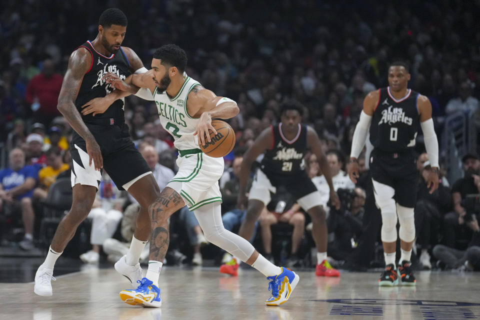 Boston Celtics forward Jayson Tatum (0) dribbles against Los Angeles Clippers forward Paul George, left, during the first half of an NBA basketball game in Los Angeles, Saturday, Dec. 23, 2023. (AP Photo/Eric Thayer)