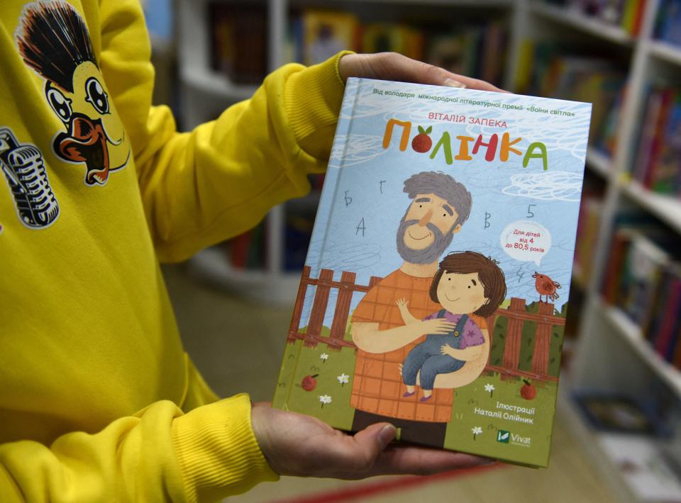 In the bookshop she manages Romana Yaremyn shows off a copy of Polinka, a Ukrainian childrens book in the western city of Lviv on April 20, 2022, one among hundreds of books evacuated from her bookshop publishing house in the embattled eastern Ukrainian city of Kharkiv. - Packed together in white parcels, the titles rescued from Kharkiv fill up what was once the children's reading room. They are just a fraction of those at the shop's publishing house in the eastern city under Russian fire. (Photo by Yuriy Dyachyshyn / AFP) (Photo by YURIY DYACHYSHYN/AFP via Getty Images)