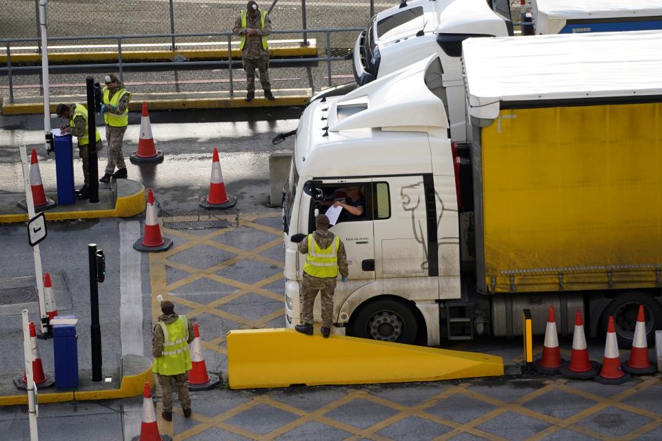 A lorry driver shows their credentials to a member of the British Army, as they enter the Port of Dover, in Dover on the south-east coast of England, on December 25, 2020, as the COVID-19 testing of drivers queueing to depart from the ferry terminal to Europe continues. - Rail and sea links between the UK and France will remain open over Christmas to clear the backlog of thousands of trucks stranded by border closures due to the discovery of a new strain of coronavirus, Britain said Thursday.  Thousands of European truckers on Wednesday spent a fourth night sleeping in the cabs of their vehicles, which are stuck close to the major cross-Channel port of Dover while the drivers wait to pass a Covid test, as required by France for travel. (Photo by Niklas HALLE'N / AFP) (Photo by NIKLAS HALLE'N/AFP via Getty Images)