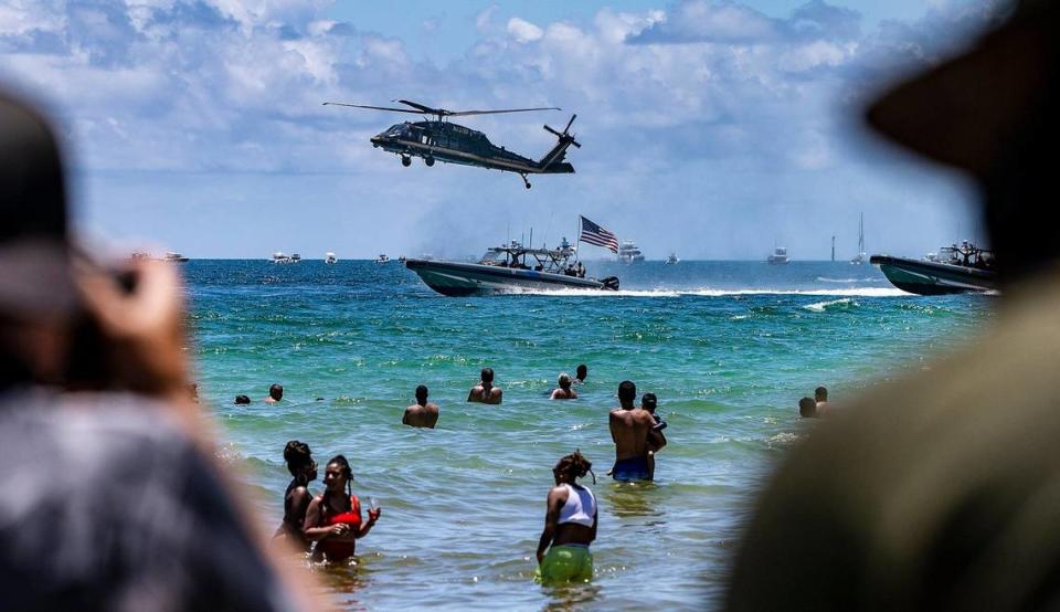 Beach goers watch a helicopter and vessels with the Air and Marine Operations performing during The National Salute to Americas Heroes Air and Sea Show presented by Hyundai in Miami Beach. on Saturday, May 29, 2021.