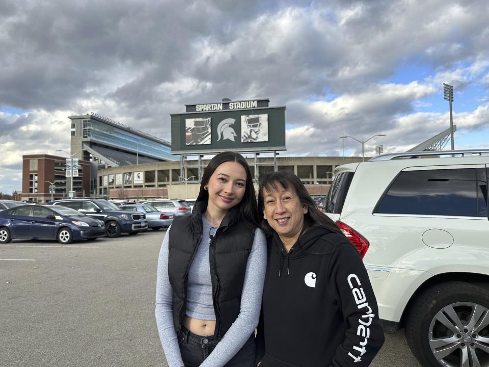 Kylie Ossege,left, poses for a photo with her mother, Marita Ossege (right), in a Spartan Stadium parking lot on the campus of Michigan State University Friday, Nov. 10, 2023, in East Lansing, Mich. KylieOssege is a Michigan State student who was severely injured in a 2021 mass shooting at Oxford High School. (AP Photo/Mike Householder)