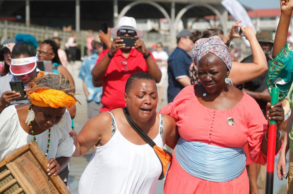 Lila Womack of Atlanta, center, is overwhelmed with emotion as she wades into the water with Patt Gunn, right, Sunday during the 8th Annual Tybee Juneteenth Wade In.