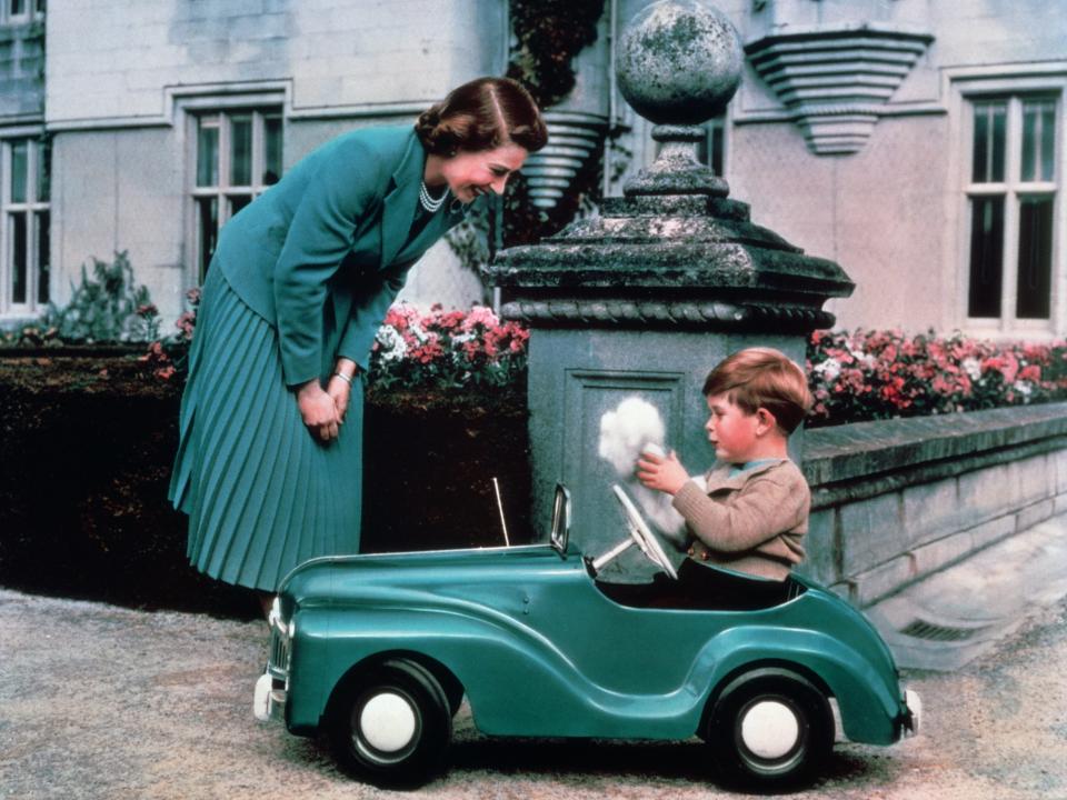 Queen Elizabeth watches Prince Charles drive a toy car at Balmoral Castle.