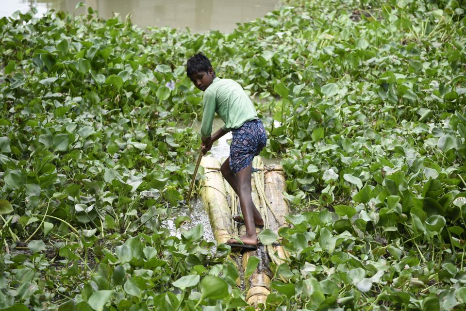 A boy uses a banana tree raft to move across a flooded area in a flood effected village in Morigaon district of Assam in India on Friday, 17 July 2020. (Photo by David Talukdar/NurPhoto via Getty Images)