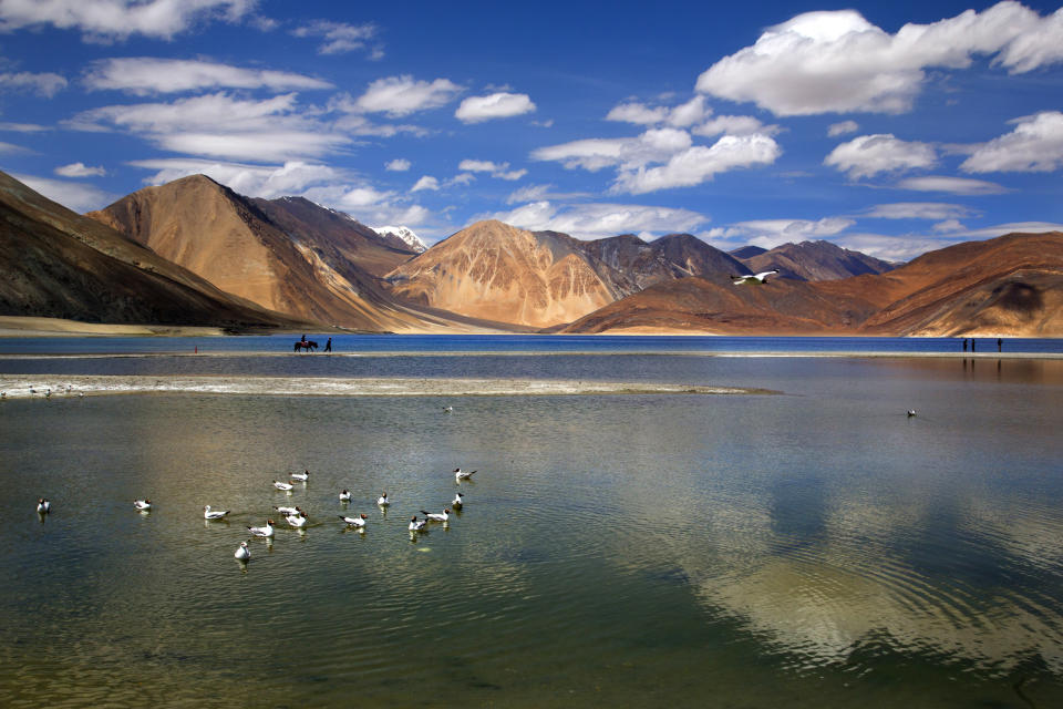 FILE-In this June 17, 2016, file photo, an Indian tourist rides on a horse back at the Pangong Lake high up in Ladakh region of India. Tensions along the China-India border high in the Himalayas have flared again in recent weeks. Indian officials say the latest row began in early May when Chinese soldiers entered the Indian-controlled territory of Ladakh at three different points, erecting tents and guard posts. (AP Photo/Manish Swarup, File)